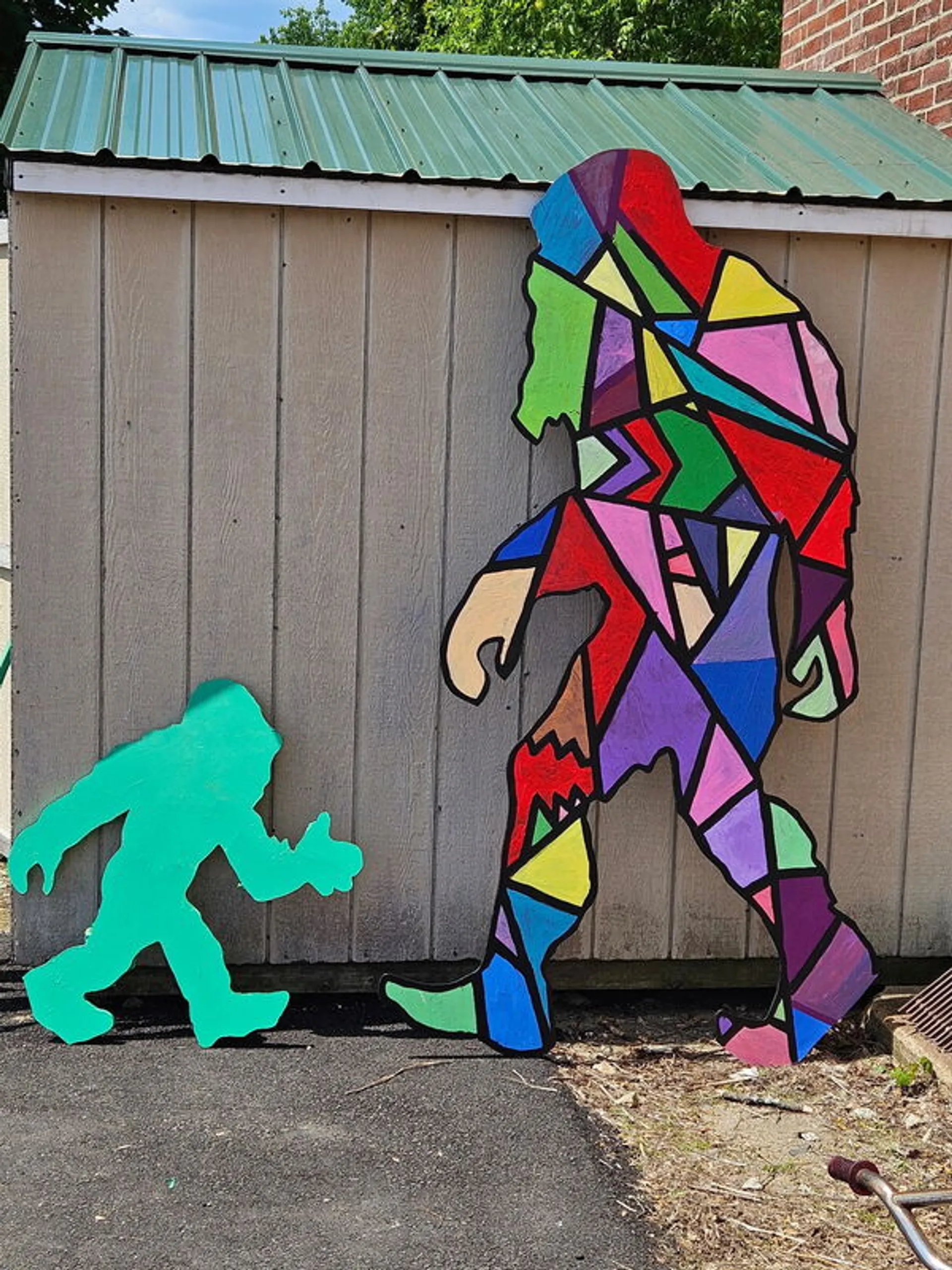Colorfully painted Bigfoot cutouts displayed on a downtown wall for the scavenger hunt