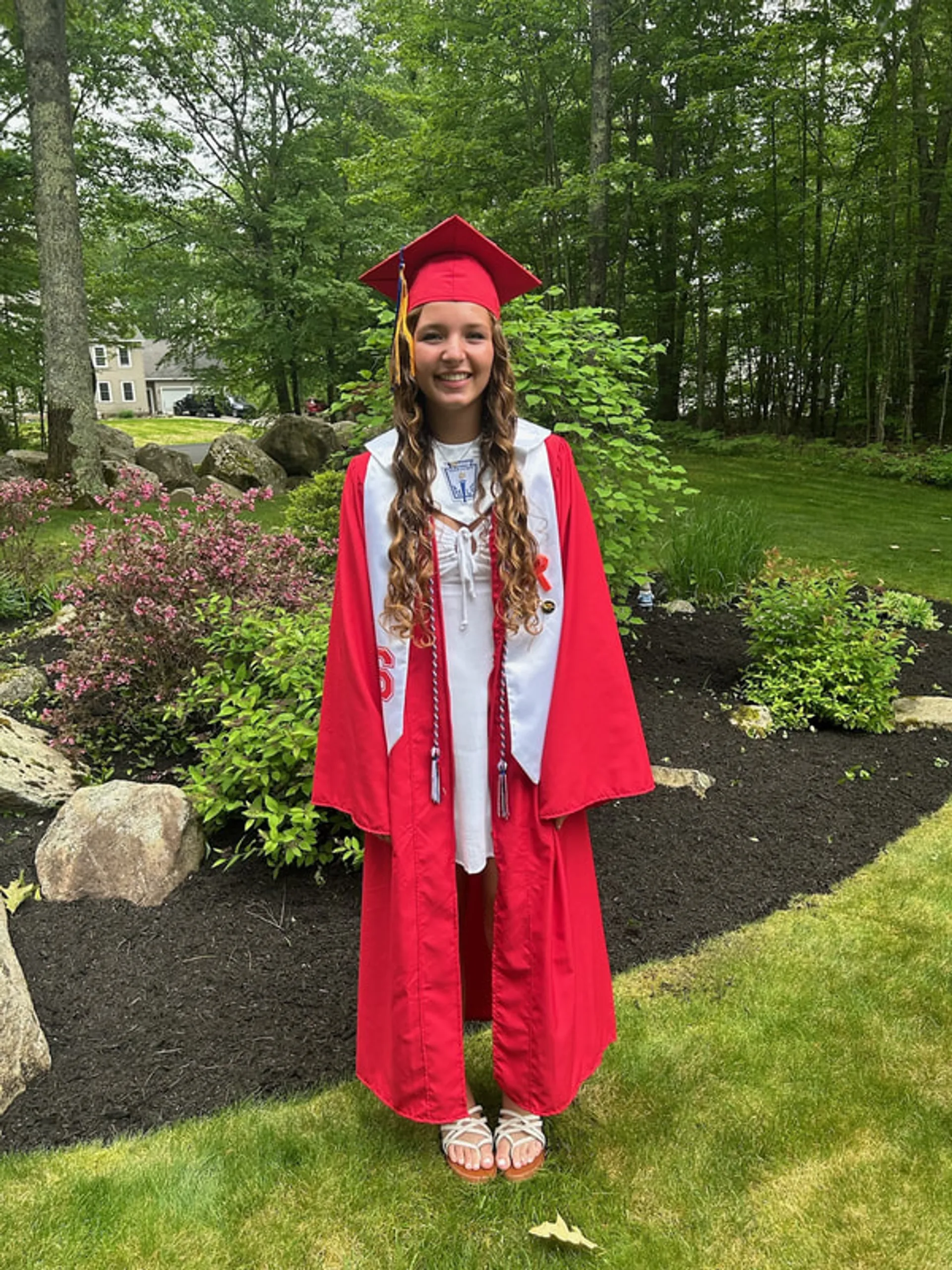 A high school graduate in a red cap and gown, recipient of the Downtown Scholarship